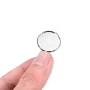 Close-up of stainless steel bezel setting pendant tray held between fingers for DIY jewelry