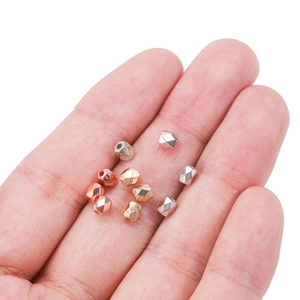 Faceted geometric CCB spacer beads in gold and silver held in hand for DIY jewelry making
