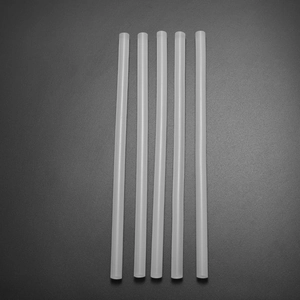 Detailed view of 5 translucent white hot melt glue sticks for DIY crafts on grey surface
