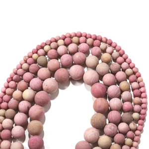 Macro shot of matte rhodochrosite beads showing natural textures and multi-size gradients