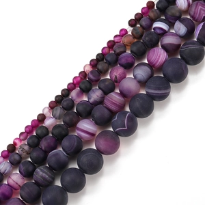 Macro detail of matte purple striped agate beads in various sizes for jewelry making