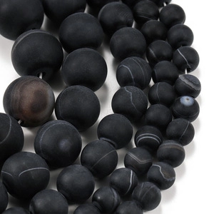 Macro detail of matte black striped agate beads in various sizes for DIY jewelry making