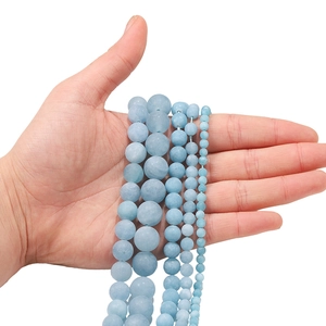 Frosted aquamarine beads in 4-12mm sizes displayed on hand for scale comparison