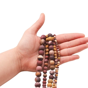 Matte natural Jasper stone beads in various sizes held in hand for jewelry making