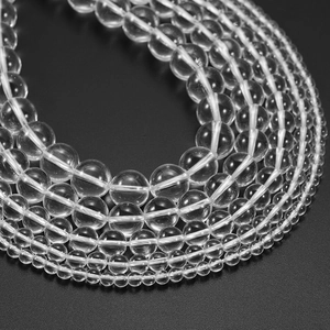 Polished clear quartz loose beads for jewelry making in various sizes on black background