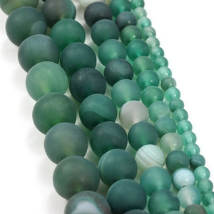 Detailed macro view of matte green striped agate beads in various sizes for DIY jewelry