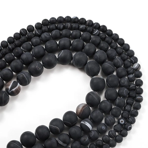 Vue macro de perles d'agate noire mate montrant des textures rubanées et un fini givré