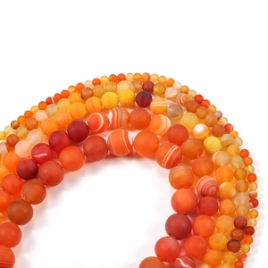 Macro shot of matte and polished orange striped agate beads for DIY jewelry making