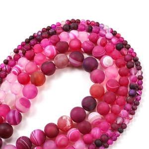 Macro detail of rose red agate beads with matte, polished, and banded textures