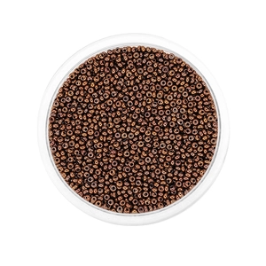 Macro shot of copper-colored metallic glass seed beads in a clear round container for DIY
