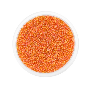 Macro view of bright orange translucent glass seed beads with iridescent finish in a round case
