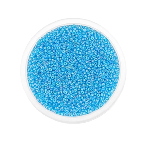 Macro shot of 2mm light blue aurora glass seed beads in a round storage container