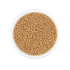 Macro shot of 2mm golden glass seed beads in a clear round container for DIY jewelry