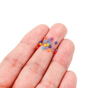 Hand holding 2mm colorful glass seed beads to show small size for DIY jewelry making