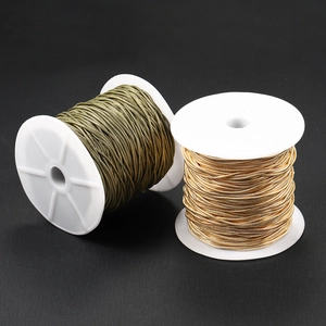 Dettaglio di catene metalliche bronzo e oro su rocchetti di plastica bianca