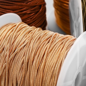 Vista macro di catene a serpente metalliche in oro e bronzo su rocchetti bianchi