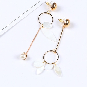 Boucles d'oreilles pendantes asymétriques dorées avec pétales blancs et perles sur fond blanc