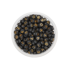 Top view of black acrylic alphabet beads with gold letters in a round storage box