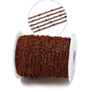 Close-up of red copper DIY beaded chain with spiral twisted wire texture on a spool