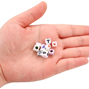 Macro shot of 6mm white acrylic letter beads on a palm for DIY jewelry making