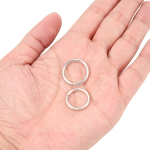 Detailed macro view of silver-plated jump rings in two sizes held in hand for DIY jewelry