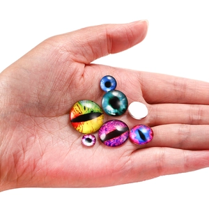 Cabochon occhio del diavolo in vetro colorato nel palmo per scala dimensioni su bianco