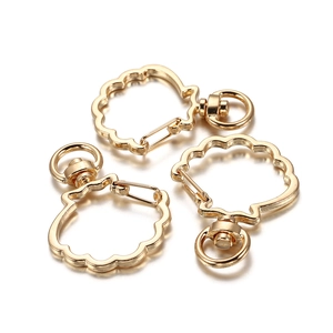Three gold shell-shaped metal lobster clasps for DIY keychains on white background