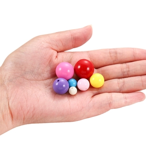 Hand holding assorted colorful acrylic round spacer beads for DIY jewelry making