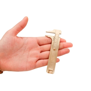 Primo piano di un mini calibro a corsoio in ottone con scale metriche e pollici in mano