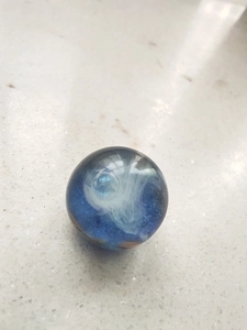 Top-down view of a galaxy-themed blue resin sphere with white nebula and glitter patterns
