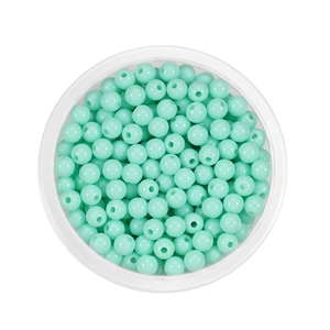 Macro view of mint green acrylic spacer beads in a clear box for DIY jewelry making