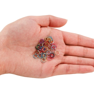 Close-up of colorful DIY aluminum jump rings for jewelry making held in palm for scale