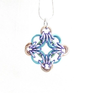 Detail of multi-color jump rings in a complex chainmail weave cross pendant