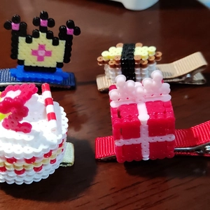 Detail van vier handgemaakte pixelkunst haarspelden met taart- en cadeaupakket bedeltjes