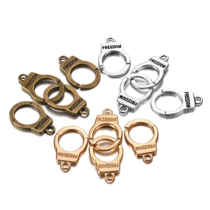 Macro detail of mini handcuff pendants in silver, bronze, and gold with Freedom engraving