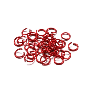 Macro detail of red aluminum jump rings scattered for DIY jewelry making material