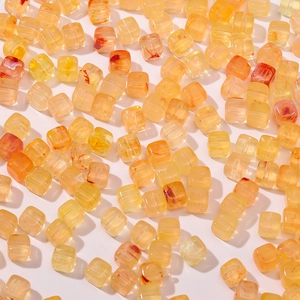 Detalle de cuentas acrílicas translúcidas amarillas en forma de cubo con texturas rojas