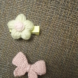 Detail van een handgebreide bloemenhaarclip en een roze stoffen strikaccessoire