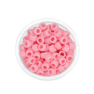 Draufsicht auf pastellrosa Acrylperlen mit großen Löchern in einem klaren Behälter