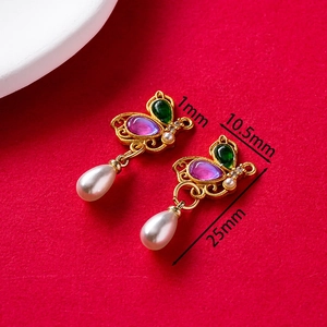 Close-up of golden butterfly earrings with purple gems and white teardrop pearls