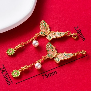 Detailed view of traditional gold butterfly pendant with pink enamel and pearl drop