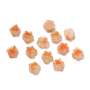 Flat lay of gradient peach resin rose charms with gold edges for DIY jewelry making