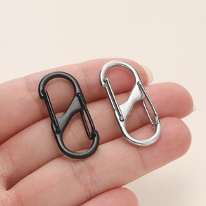 Makroansicht von S-förmigen Karabinern in Schwarz und Silber mit Doppelclip in der Hand
