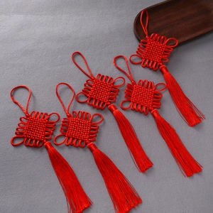 Close-up of five handmade red Chinese knot tassels with lucky knots on a grey surface
