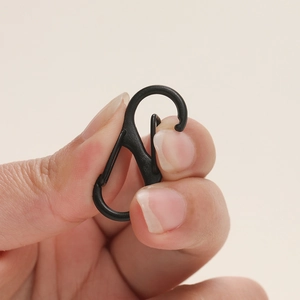 Detailaufnahme von schwarzem S-Form Doppelkarabiner in der Hand für Größenvergleich