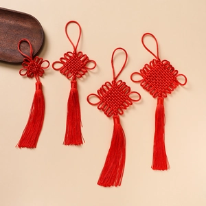 Detailed view of four red Chinese knots with silk tassels on a warm background