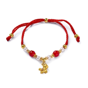 Detail of red braided New Year bracelet featuring a golden pig charm and pearls