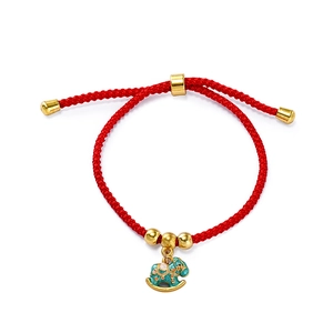 Close-up of red woven bracelet with gold beads and a green enamel horse charm pendant