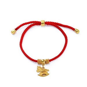 Macro view of woven red string bracelet with a golden horse charm for the New Year