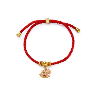 Close-up of red woven bracelet featuring a gold rocking horse pendant and metallic beads